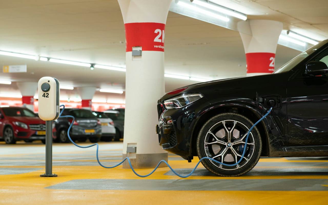 Crni električni auto se puni na punjaču u garaži