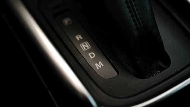 Detalj selektora automatskog menjača sa oznakama P R N D M i kožnim manžetom
